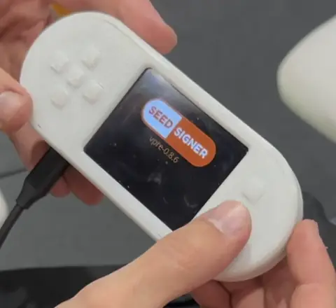 SeedSigner (pre-release 0.8.6 boot screen) in a 3D-printed gamepad-style case